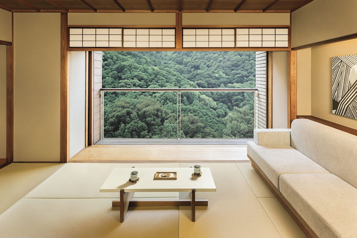 A traditional Japanese room with tatami flooring, a low table with a framed picture, and a sofa.
