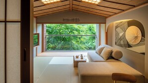 A room with tatami flooring, a sofa, a wooden table, and a view of greenery through large windows. - Hoshino Resorts KAI Hakone (Hakone)