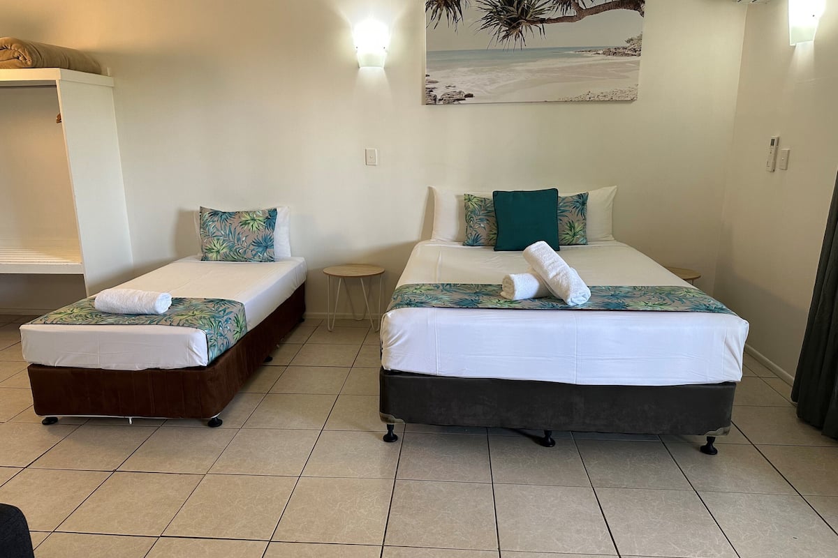 A hotel room with two beds, a small round table, and a wall-mounted artwork.