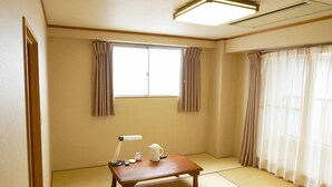 A traditional Japanese room with tatami flooring, a low wooden table with a kettle and teapot, and two windows with curtains. - Hotel Abest Kochi (Kochi)