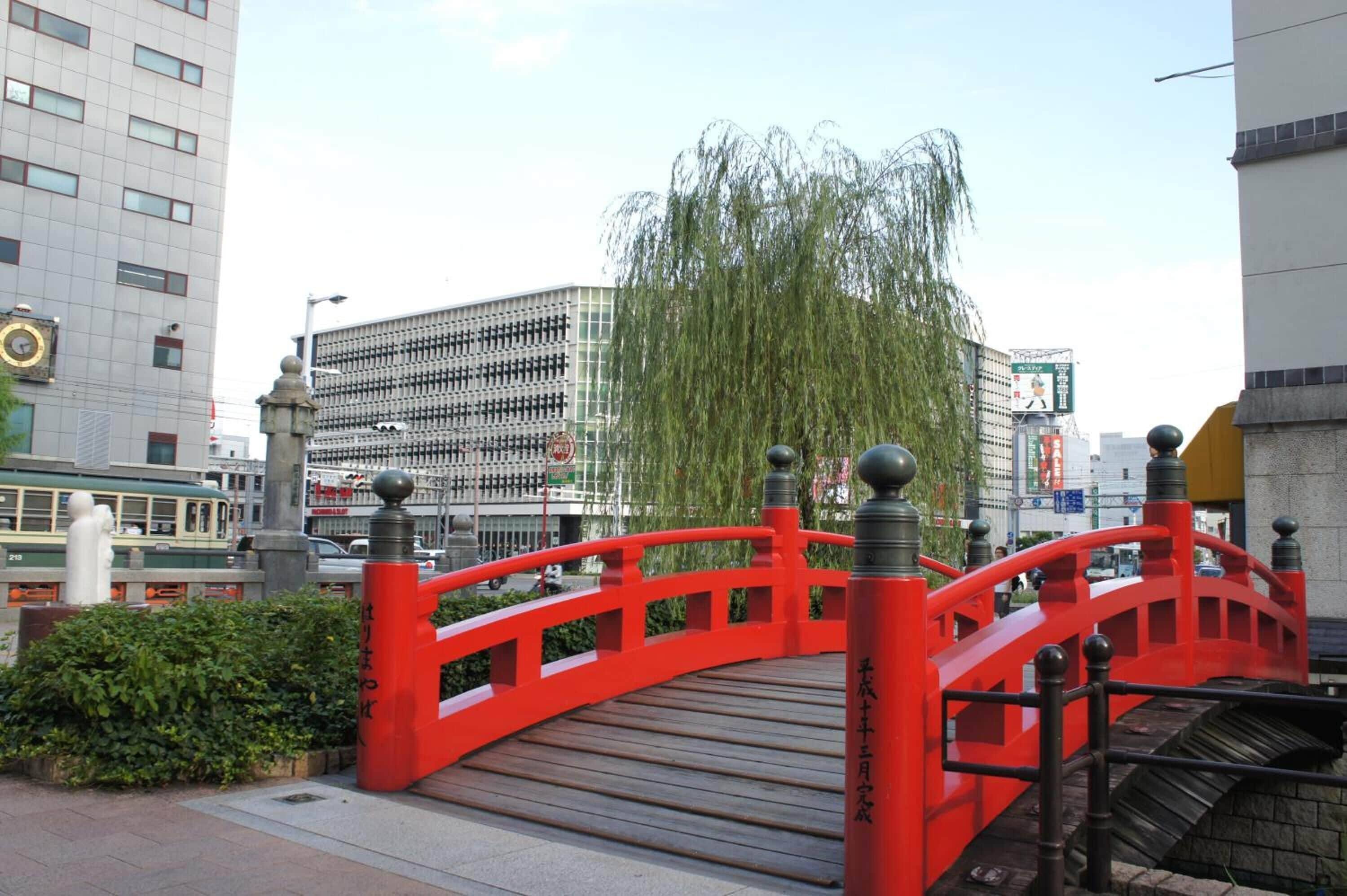 A red bridge with stone pillars and a wooden walkway.