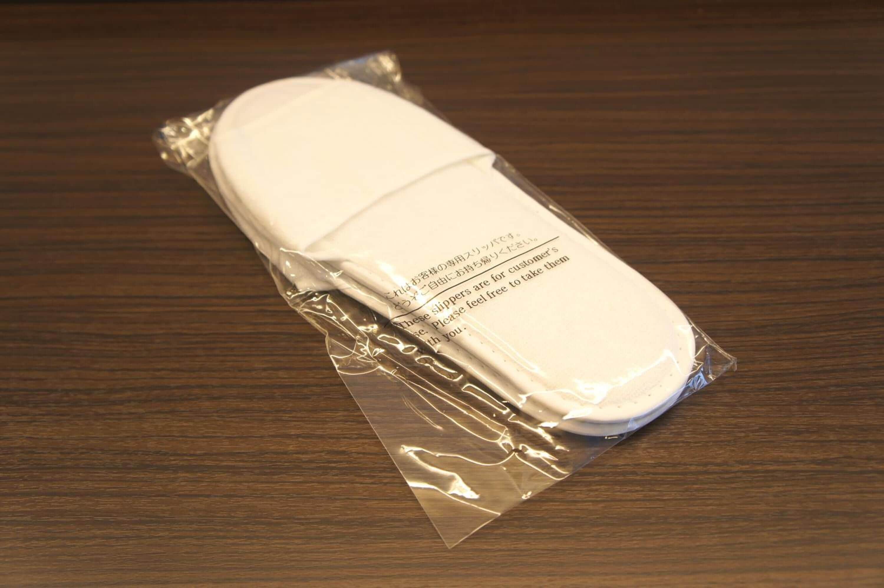 Un objeto blanco dentro de una bolsa de plástico transparente sobre una superficie de madera.