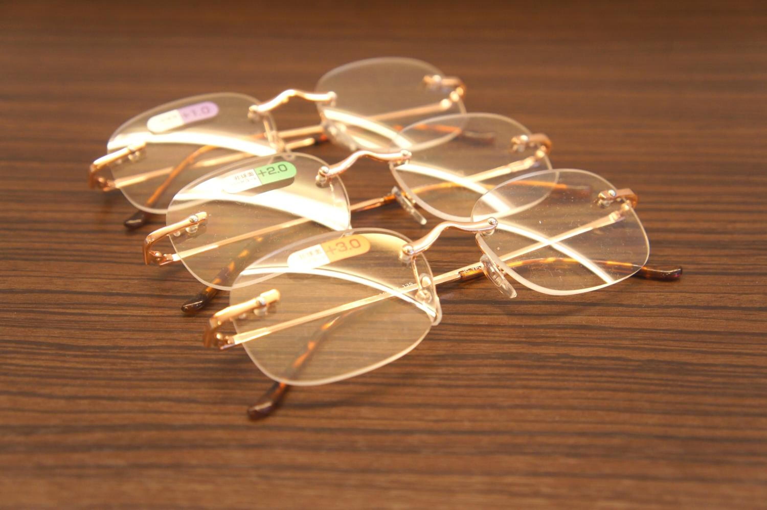 A pair of eyeglasses with metal frames and clear lenses, lying on a wooden surface.