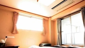 A hotel room with a bed, a bedside table, a lamp, and a window with curtains. - Hotel Abest Kochi (Kochi)