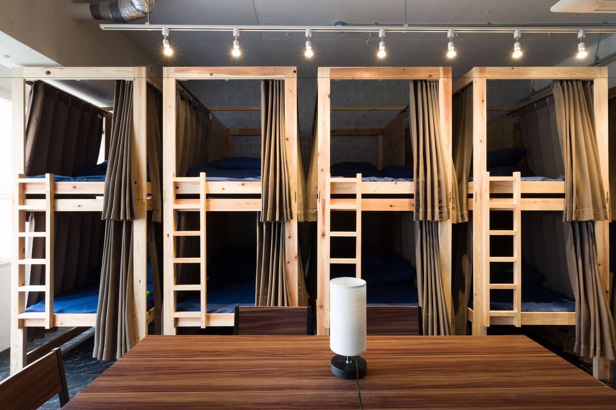 A room with bunk beds, a wooden table, and a lamp.