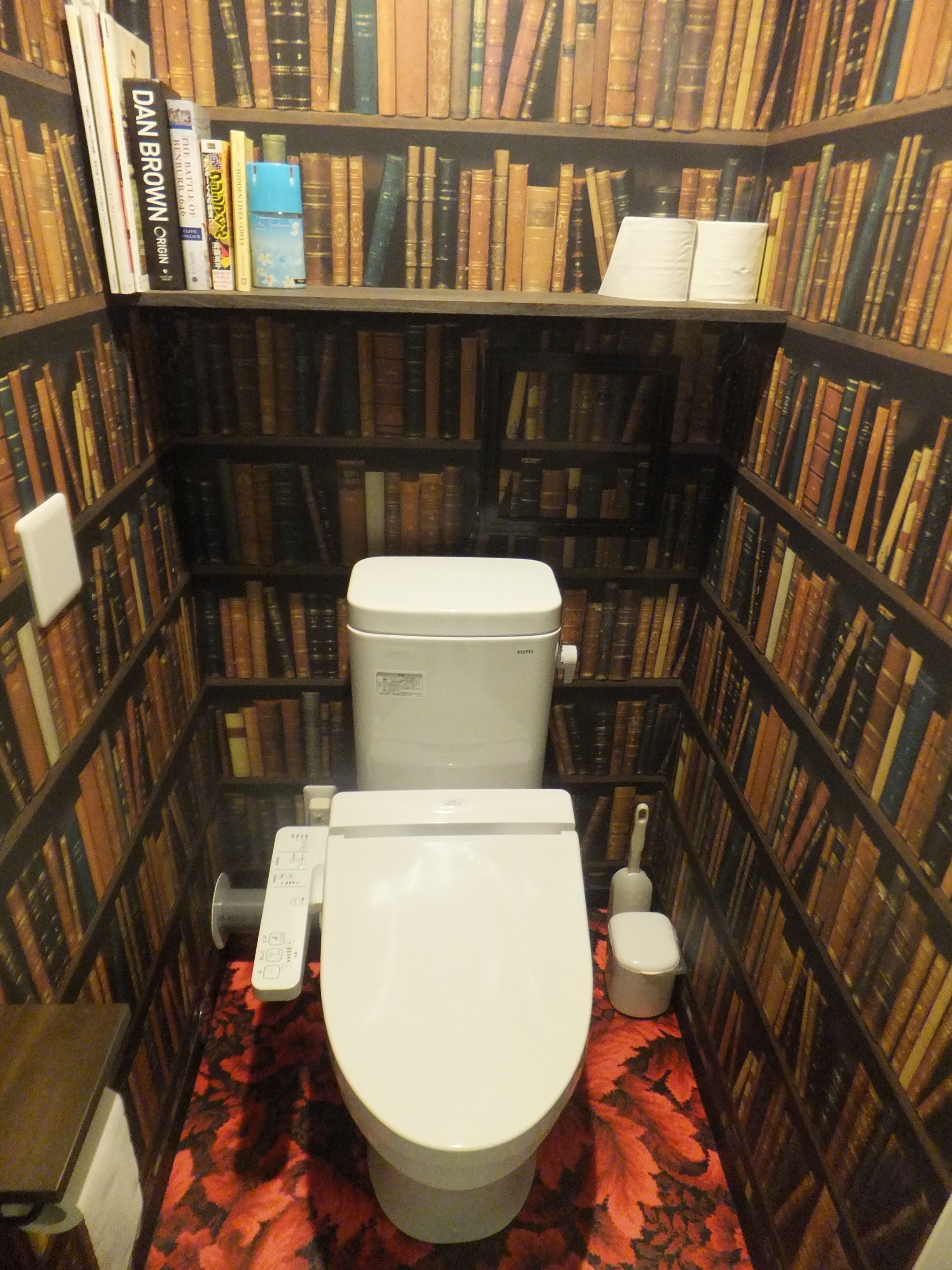 A small, enclosed bathroom with a toilet, a TOTO brand toilet, and a white toilet paper holder.