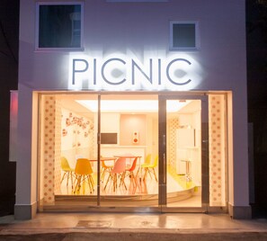 A restaurant named "PICNIC" with a glass entrance, visible interior seating, and a modern design. - Picnic Hostel Osaka (Osaka)