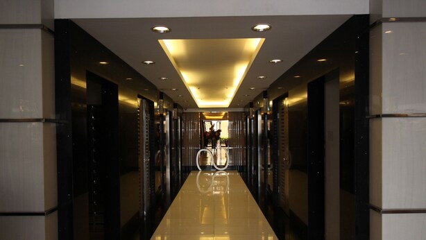 A modern hotel corridor with a reflective floor, recessed lighting, and a central decorative element. - Solemare Parksuites Condo R Us (Parañaque)