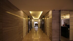 A modern hotel corridor with a long, polished floor, mirrored walls, and a central elevator. - Solemare Parksuites Condo R Us (Parañaque)