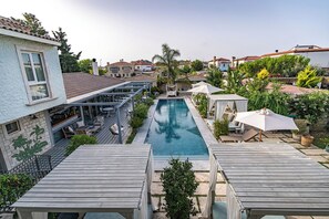 Un espace piscine doté d’un coin salon abrité, d’un petit jardin et d’une vue sur les bâtiments environnants.