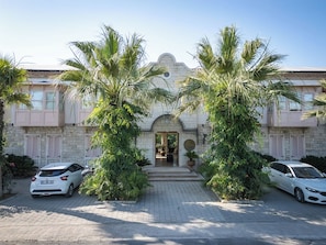 A building with a stone facade, a central entrance, and two cars parked in front. - Casa Luna Hotel Alaçati (Cesme)