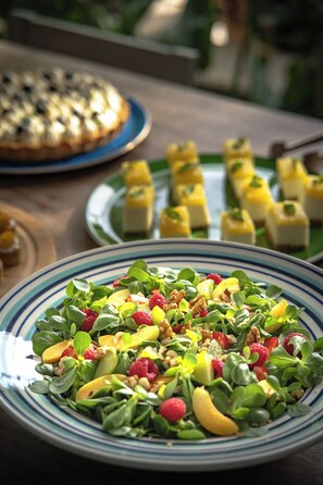 Une table garnie d’une variété de plats, notamment une salade, des fruits et des desserts.