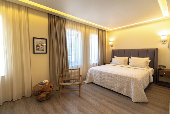 A hotel room with a bed, a chair, a wooden side table, and a picture on the wall. - Casa Luna Hotel Alaçati (Cesme)