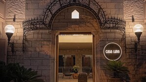 Un bâtiment en pierre avec une entrée en arc de cercle, une enseigne indiquant « Casa Luna » et un banc à l’extérieur.