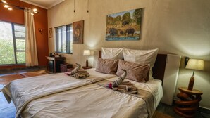 Un dormitorio amplio con una cama grande, un escritorio y una silla. Hay cuadros en las paredes y una ventana con cortinas.