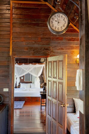 A wooden interior with a bed, a hanging clock, and a door leading to another room. - The White House Boutique Chiangrai (Chiang Rai)