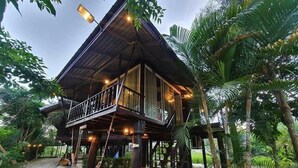 A two-story wooden house with a balcony, surrounded by tropical vegetation. - The White House Boutique Chiangrai (Chiang Rai)