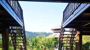 An outdoor swimming pool with a tiled floor, surrounded by a wooden deck and a view of a green landscape. - The White House Boutique Chiangrai (Chiang Rai)