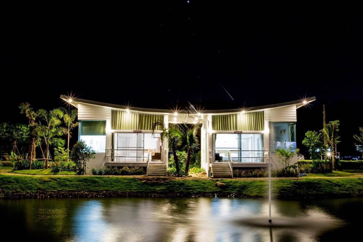 A modern, two-story house with a curved roof, large windows, and a well-lit entrance.