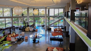 A spacious lobby with a piano, seating areas, and large windows offering views of the outdoors.