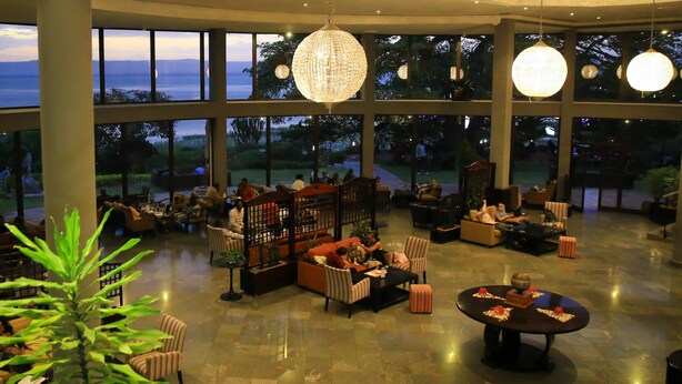 A spacious indoor area with large windows, comfortable seating, and decorative lighting.