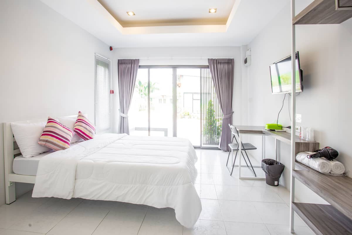 A modern hotel room with a large bed, a desk, and a TV.