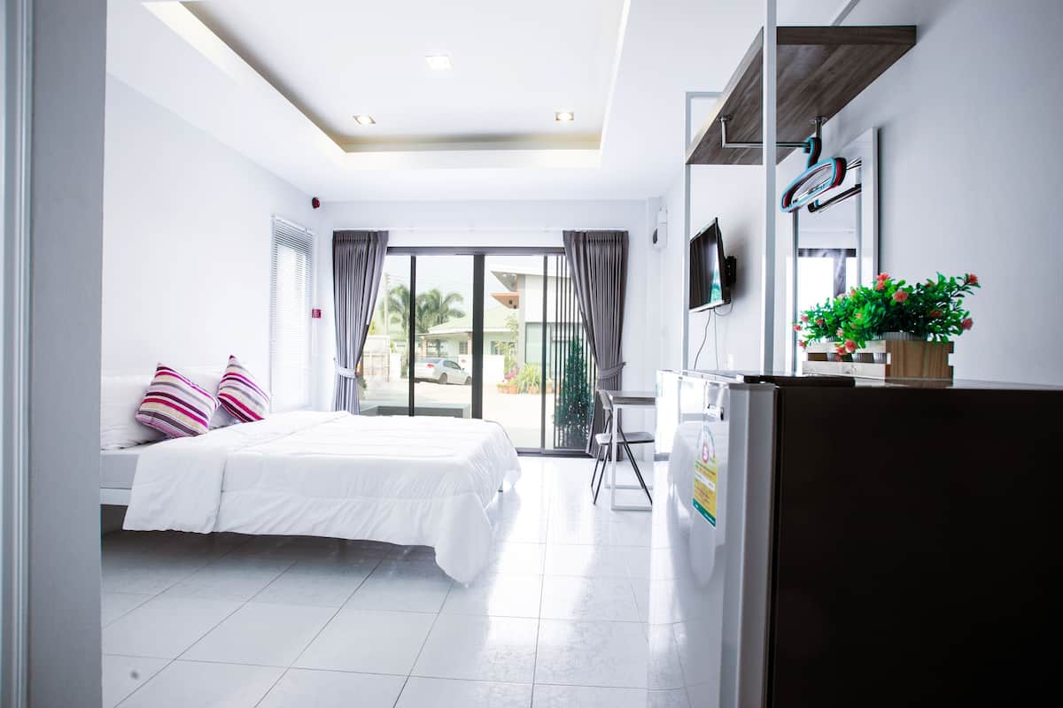 A modern hotel room with a bed, a desk, a TV, and a view of the outside.