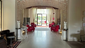 Uma área de estar ampla com um arco de tijolos, móveis vermelhos e vista para o exterior.