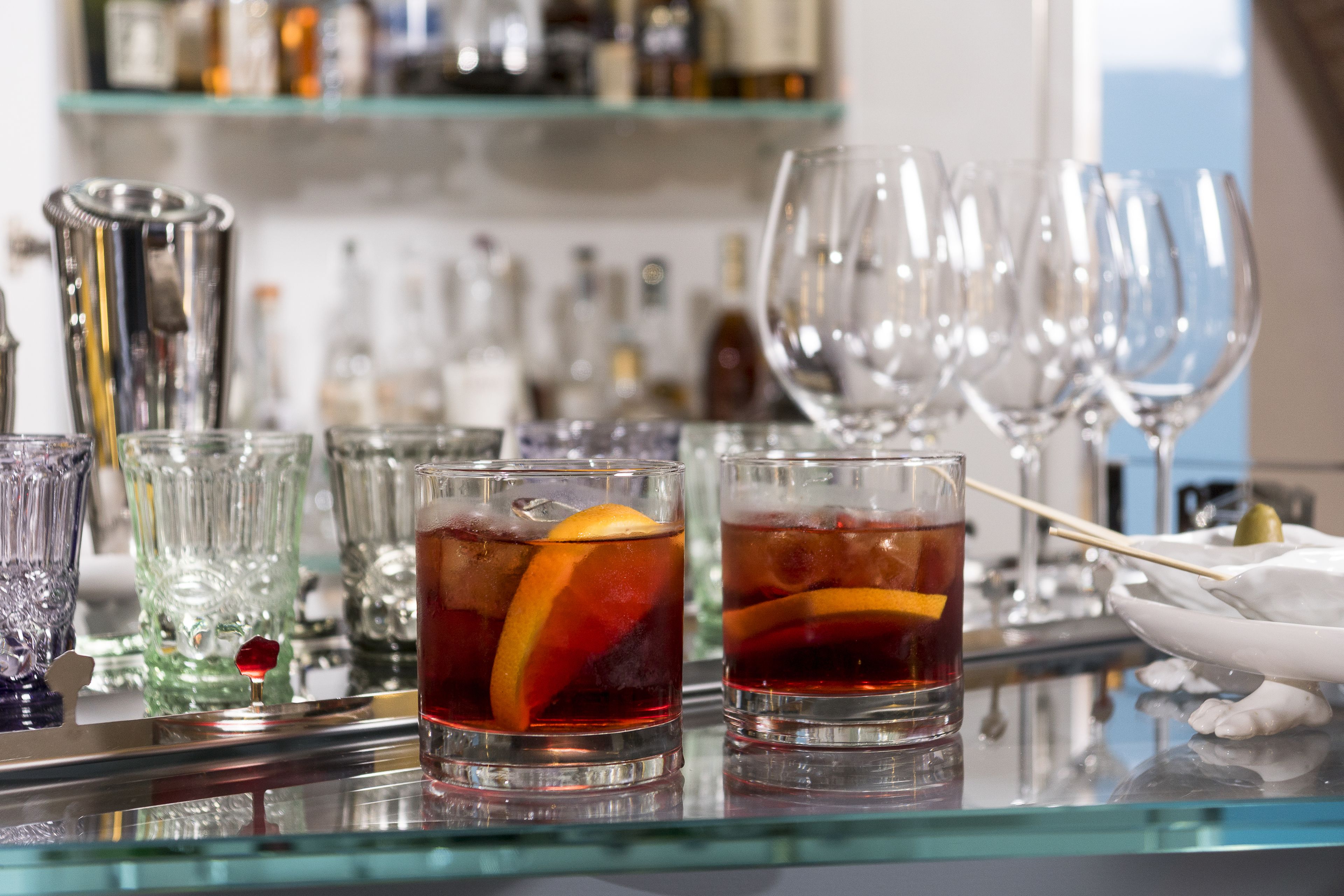 A bar area with glasses of red beverages, ice, and a decorative item on the counter.