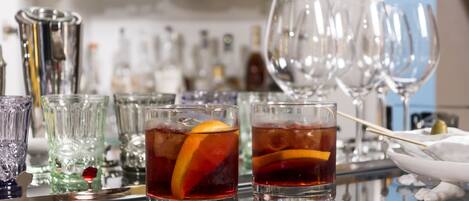 A bar area with glasses of red beverages, ice, and a decorative item on the counter.