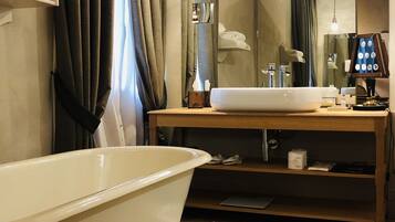 Un bagno con una vasca freestanding, un mobile lavabo in legno e un ampio specchio.
