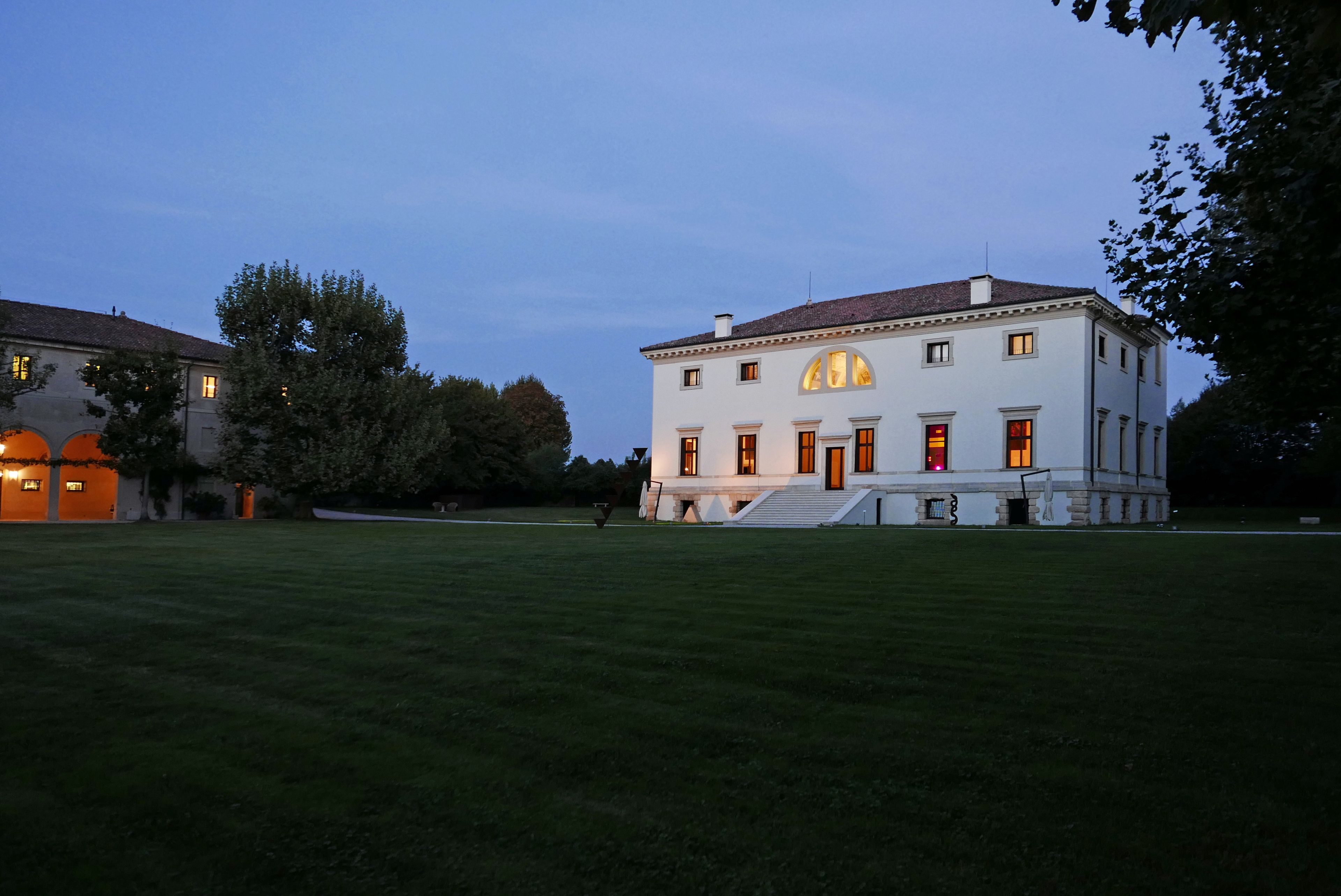 Un grand bâtiment blanc à la façade symétrique, doté de nombreuses fenêtres et d’une entrée centrale avec des marches.
