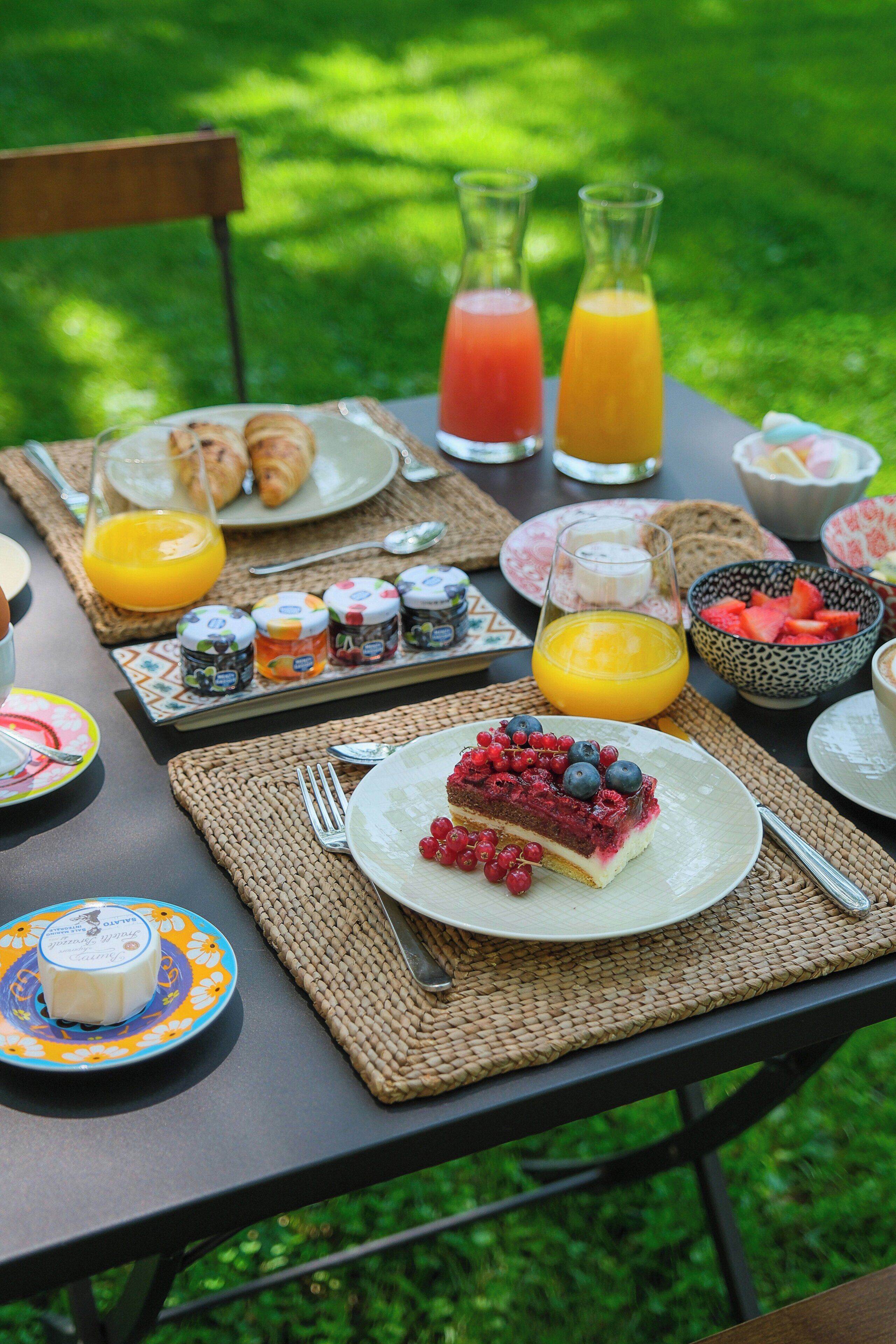 Un montaje para picnic con comida, bebidas y salsas sobre una mesa al aire libre.
