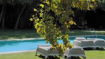 A poolside area with lounge chairs and a tree.