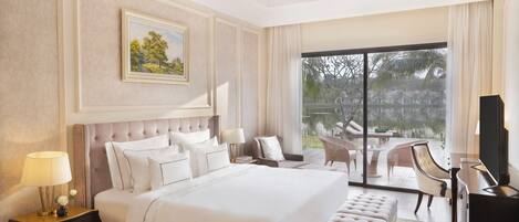 A spacious bedroom with a large bed, a nightstand, a dresser, and a television.