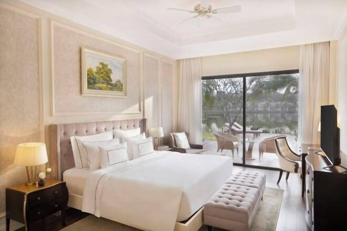 Une chambre d’hôtel dotée d’un grand lit, d’un bureau, d’une chaise, d’une télévision et d’un balcon aménagé avec du mobilier d’extérieur.
