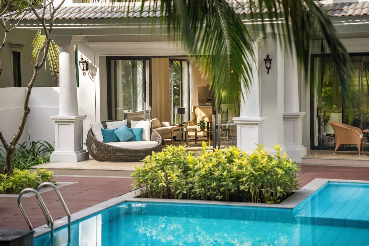 Un espace piscine aménagé avec un canapé en osier, une table à manger et une chaise.
