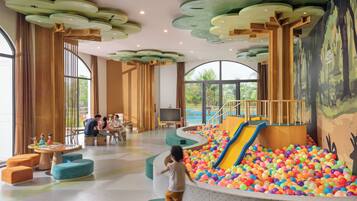 Kids can play in the ball pit with a slide, while adults relax nearby in comfortable seating.