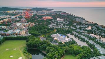 An aerial view of a coastal resort area with a large Ferris wheel, a golf course, and a marina.