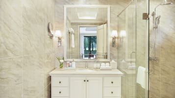Un bagno moderno con cabina doccia in vetro, uno specchio grande e una parete rivestita in marmo.