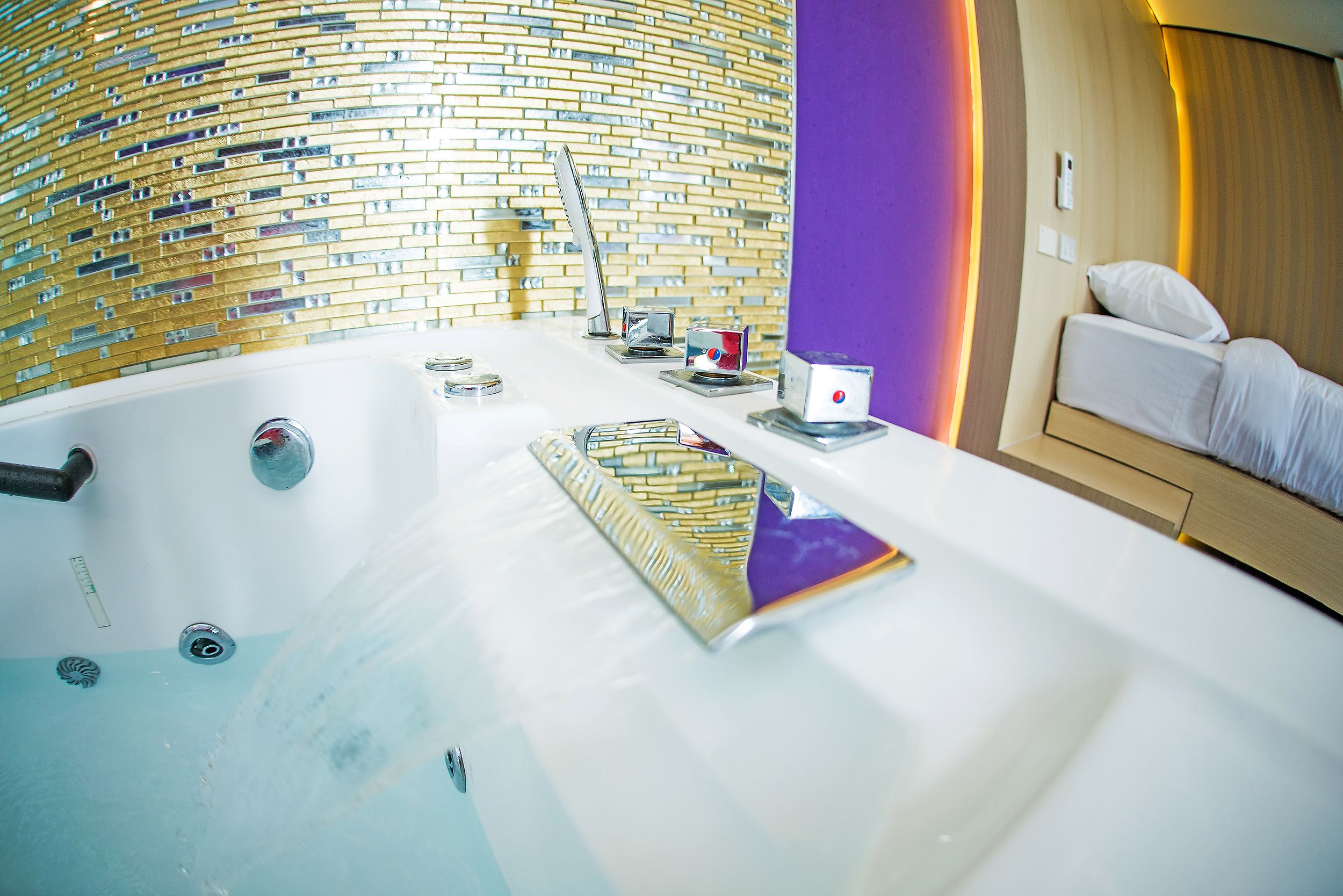A modern bathroom with a large bathtub, a shower, and a toilet. There is a towel rack and a small table with a cup and a tissue box.
