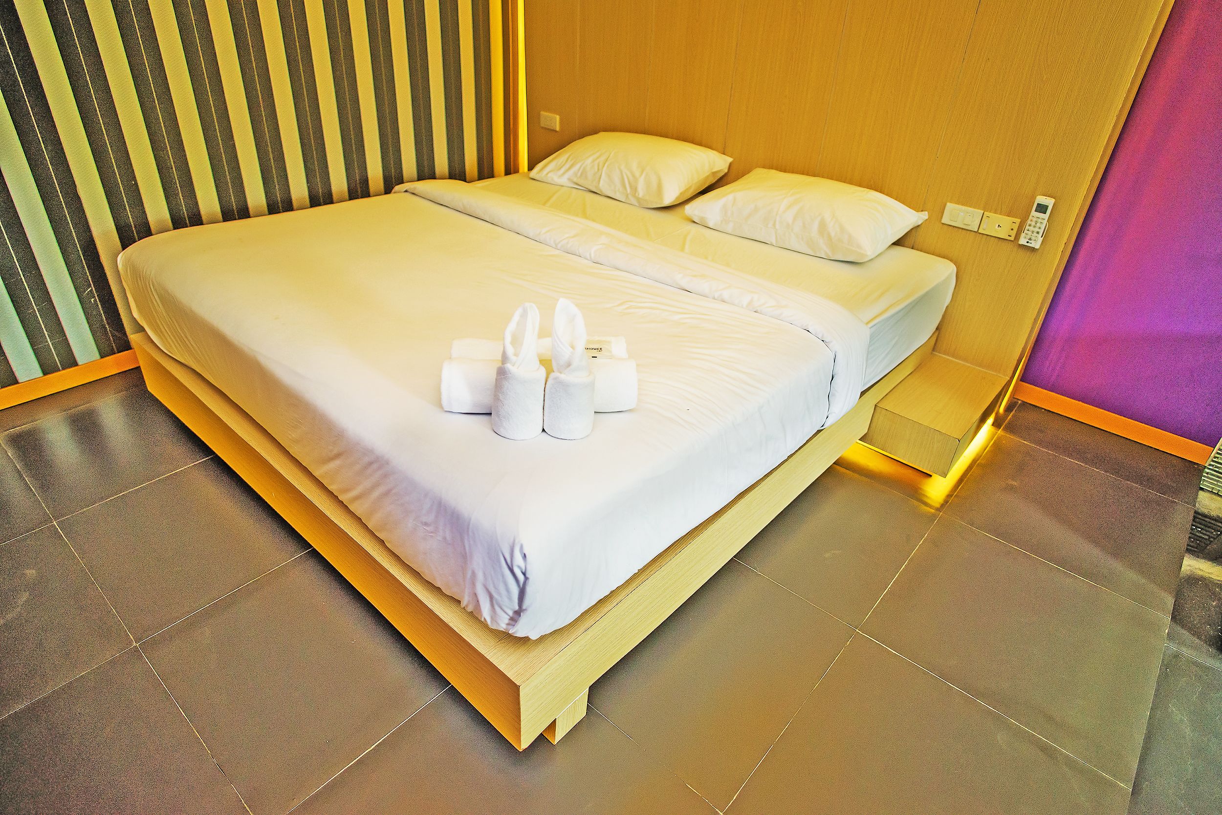 A neatly made bed with white linens and towels, a wooden headboard, and a bedside telephone.