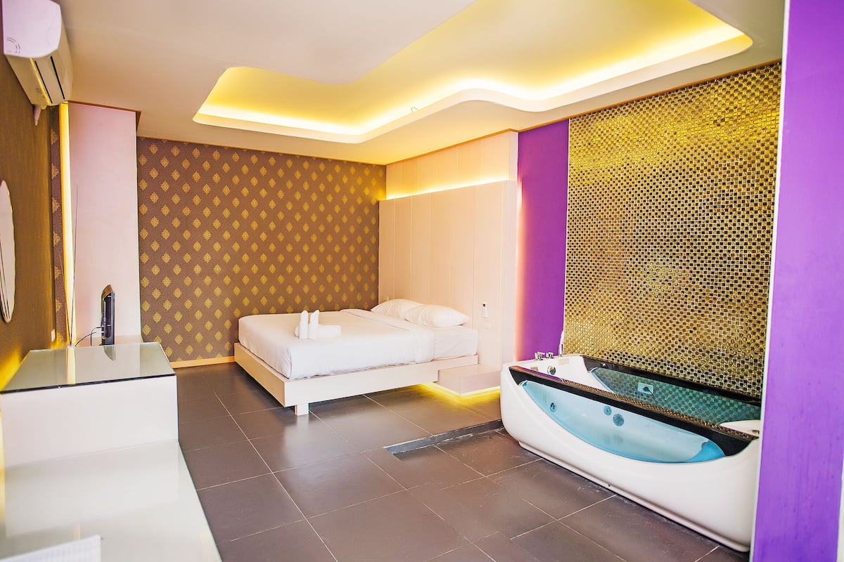 Una habitación de hotel moderna con cama, tocador de vidrio, bañera y pared con estampado.