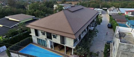A two-story house with a flat roof, a swimming pool, and a small garden.