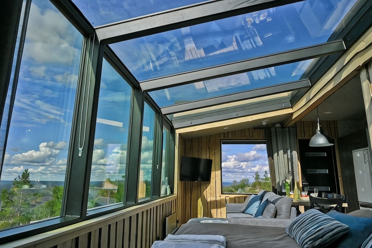 Een kamer met een groot dakvenster, een bed, een televisie en uitzicht op het landschap.