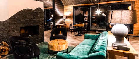 A cozy interior with a fireplace, plush green sofa, and wooden furniture.