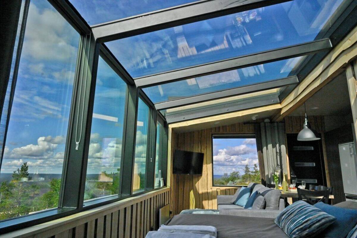 Ein Zimmer mit einer großen Glasdecke, einem Bett, einem Fernseher und einem Essbereich mit Tisch und Stühlen.
