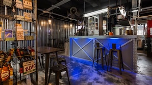 A bar area with a counter, stools, and shelves stocked with bottles.