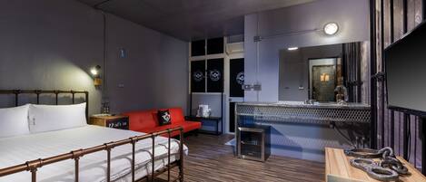 Una habitación de hotel moderna con una cama grande, un sofá rojo, un escritorio pequeño y un espejo.