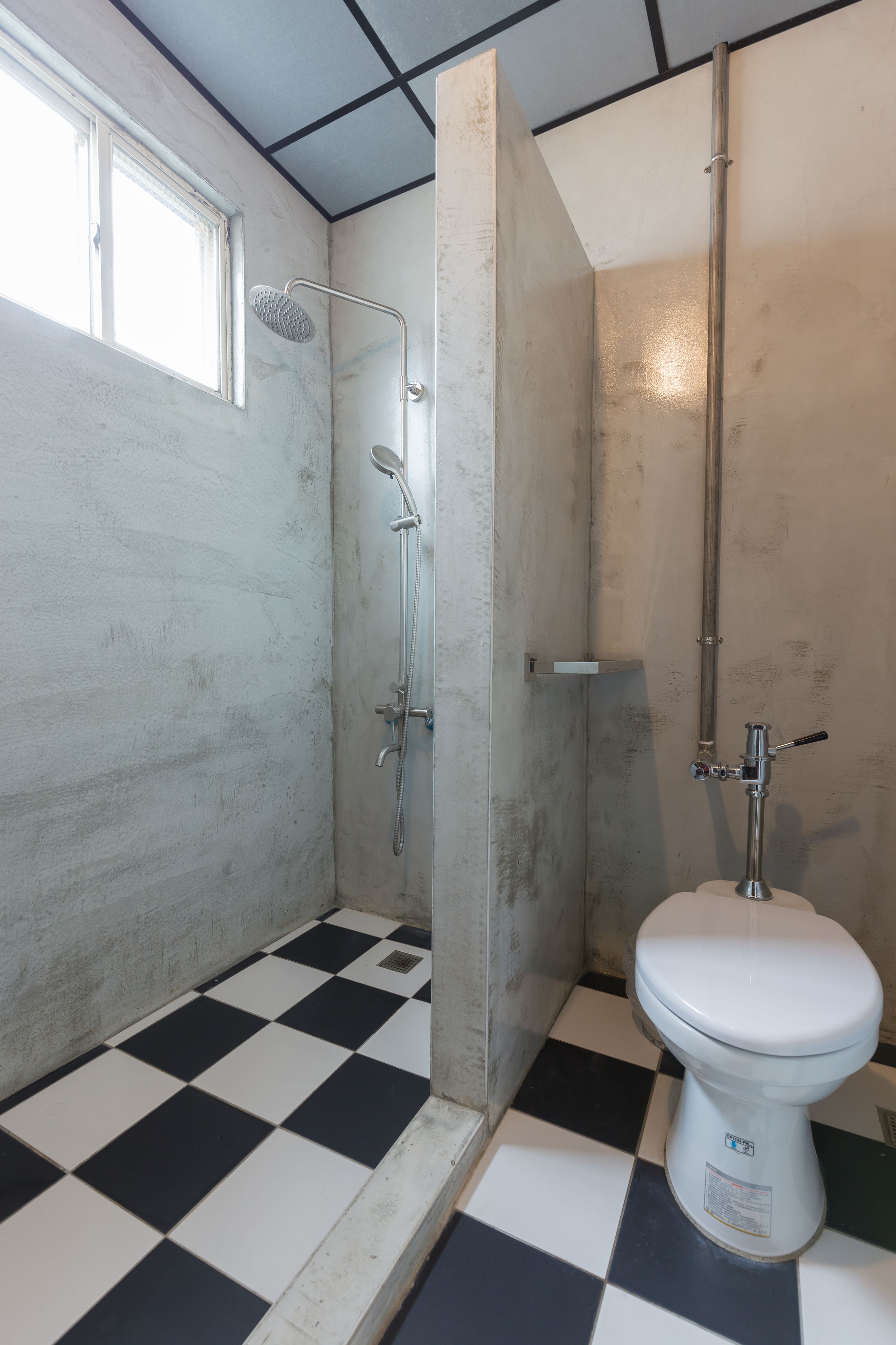 A bathroom with a black and white checkered floor, a white toilet, and a shower area with a glass door.